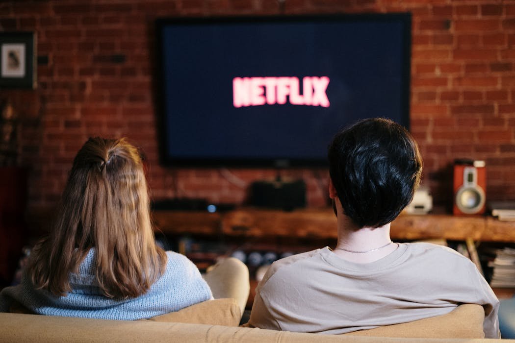 Person watching streaming movies on TV with popcorn at night