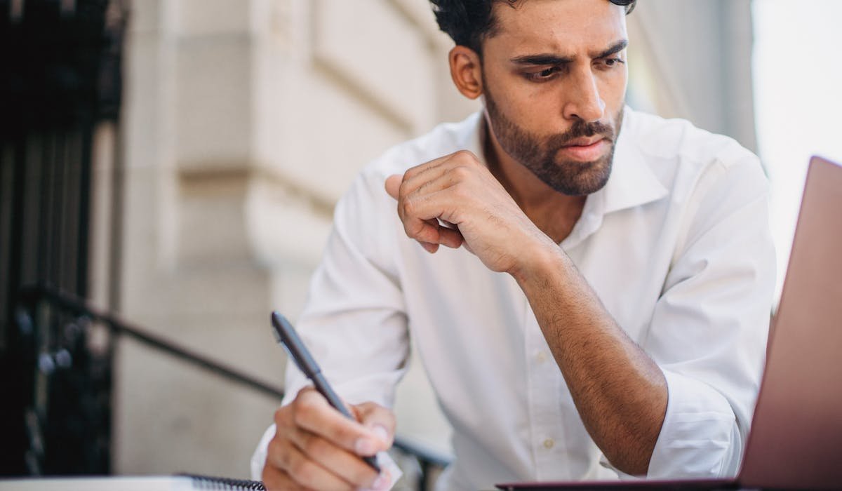 Person taking notes on laptop and notebook - best note-taking apps compared 2026